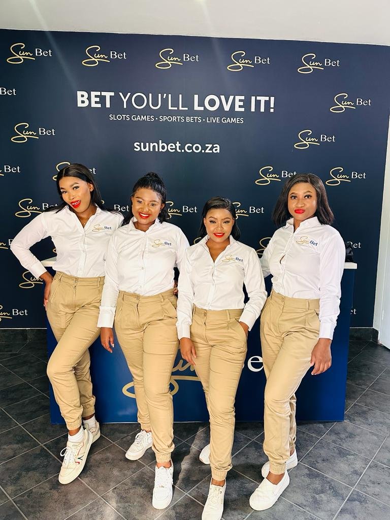 Isilumko-Activate Street-level marketing teams of four women standing in front of a sign that says bet you love it.