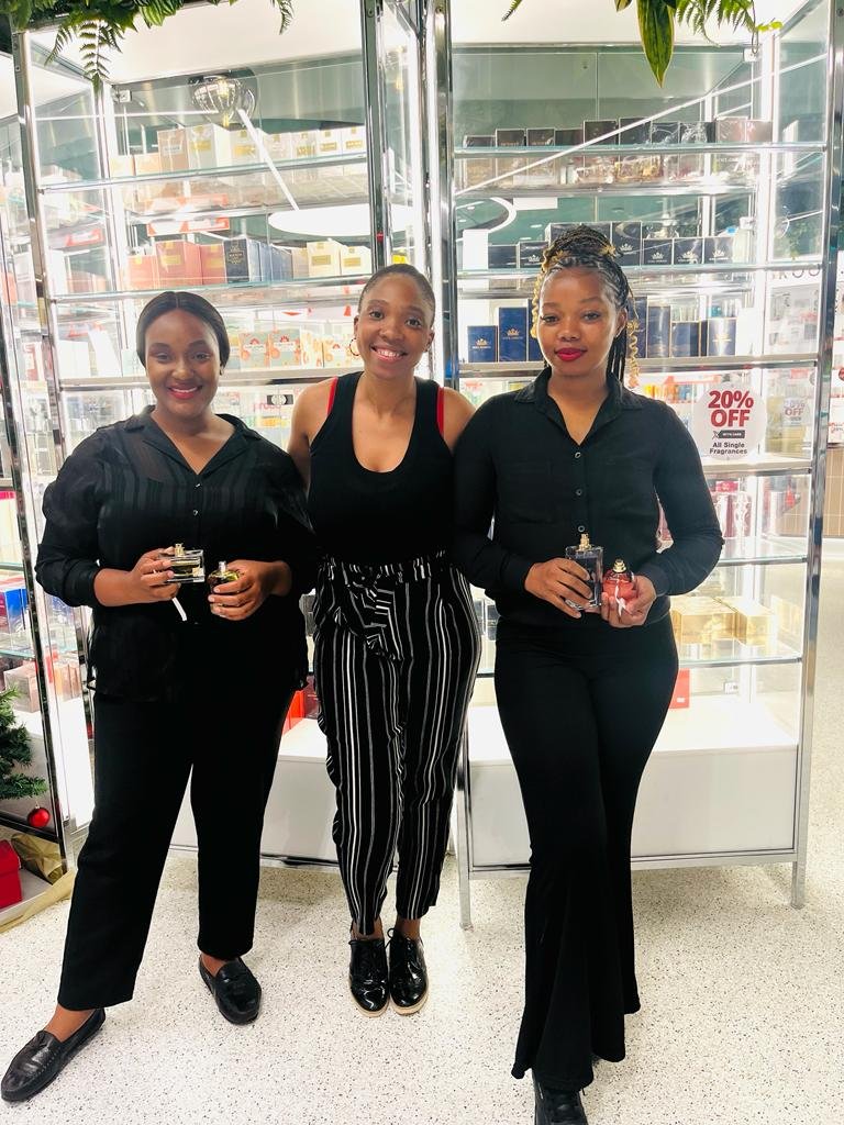 Isilumko-Activate Three women showcasing marketing for a business in front of a display case.