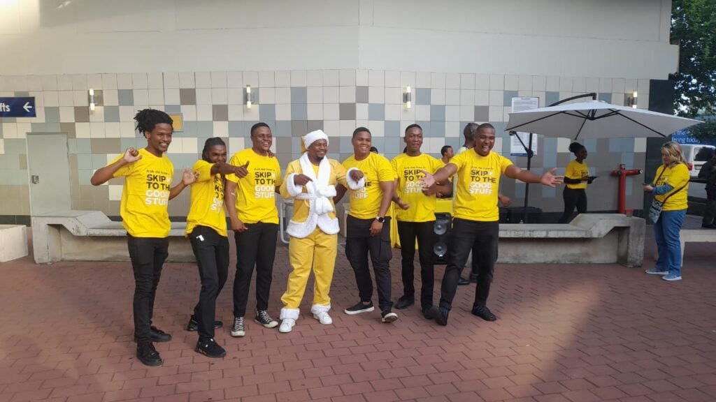 Isilumko-Activate A group of people in yellow shirts posing for a picture during a marketing event for a business.