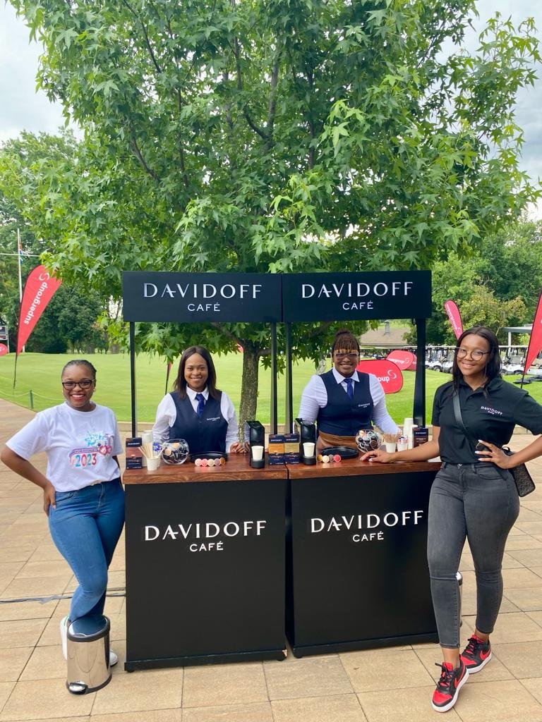 Isilumko-Activate Three women standing in front of a davidoff wine bar, discussing marketing ideas for their small business.
