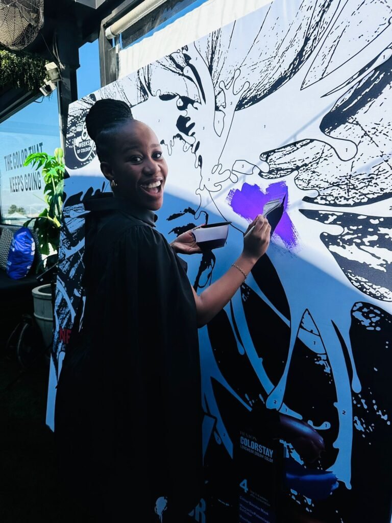 Isilumko-Activate A woman is painting on a large canvas, showcasing her artistic talent and creativity.
